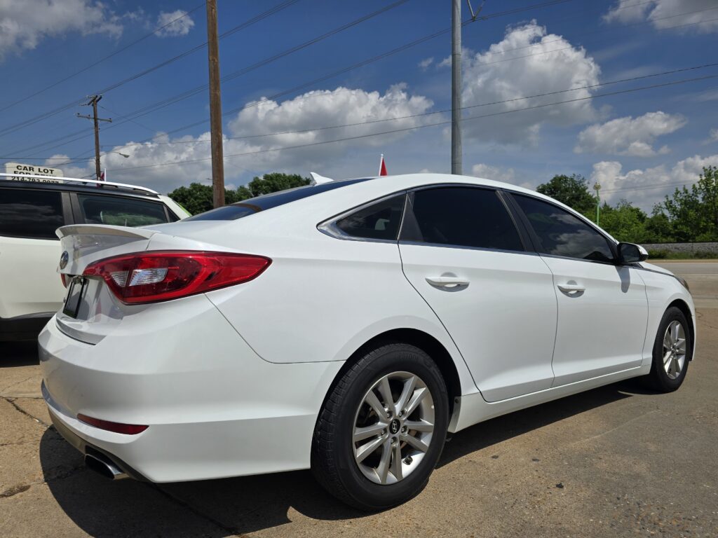 White sedan parked beside a white SUV in a sunny parking lot, with a blue sky and power lines overhead.