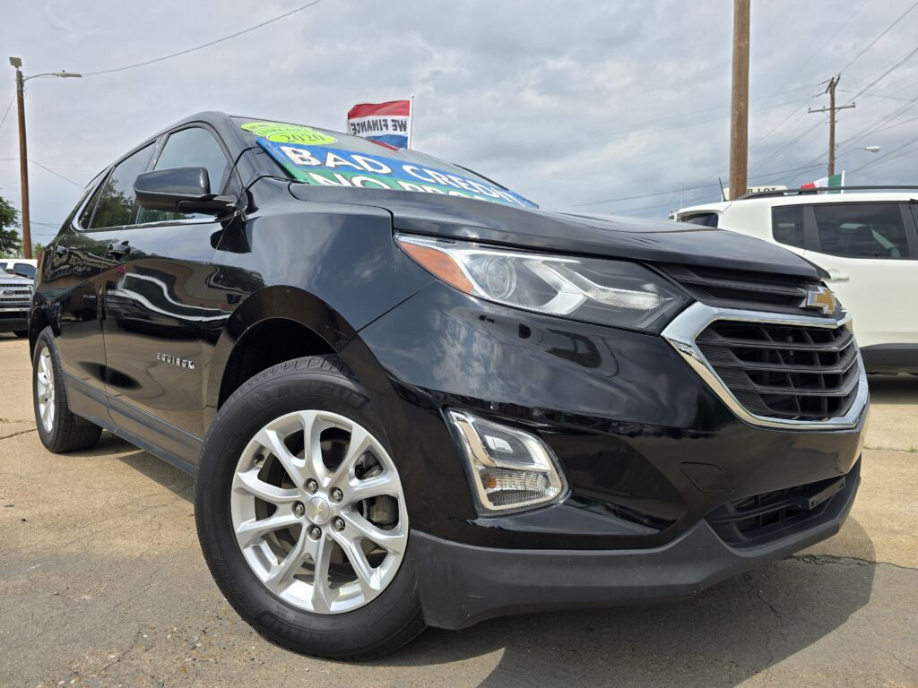 Close-up of a black Chevrolet SUV at a dealership with a bright sale sign on its windshield reading 'BAD CREDIT'.