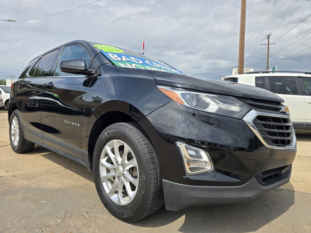 Close-up of a black Chevrolet Equinox at a dealership, with a bright blue-green sale sign on the windshield.