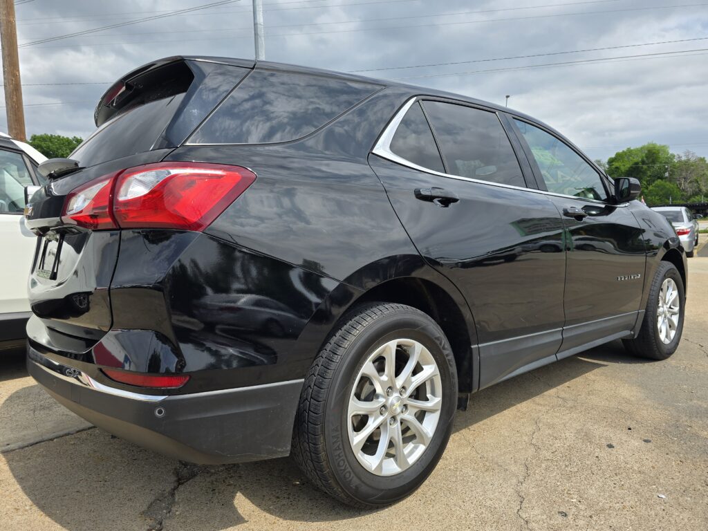 Black mid-size SUV shown from the rear-right three-quarter view in a parking lot, with chrome trim around the windows and visible rear taillight.