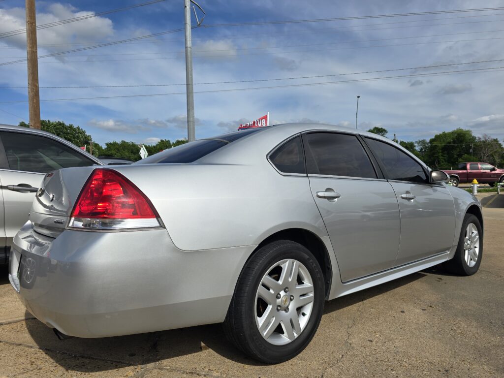 Silver sedan parked in a lot, showing rear and side with tinted windows and chrome trim.