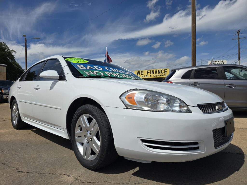White sedan at a car dealership with a large green sign reading 'Bad Credit No Problem' on the windshield.