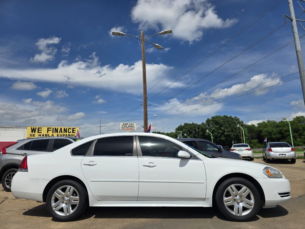 White cars parked in a lot under a blue sky with clouds; a yellow 'WE FINANCE' sign visible in the background.