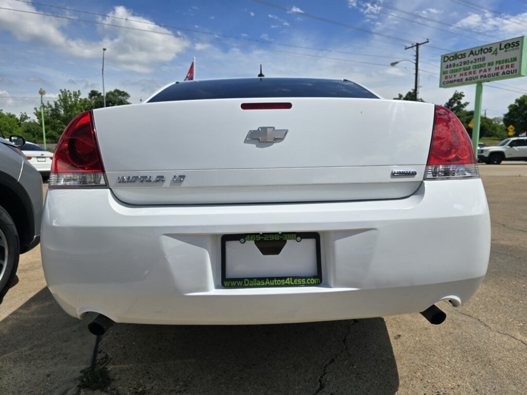 Rear view of a white Chevrolet Impala LT with visible bowtie emblem and Dallas Autos 4 Less license plate frame in a dealership lot.