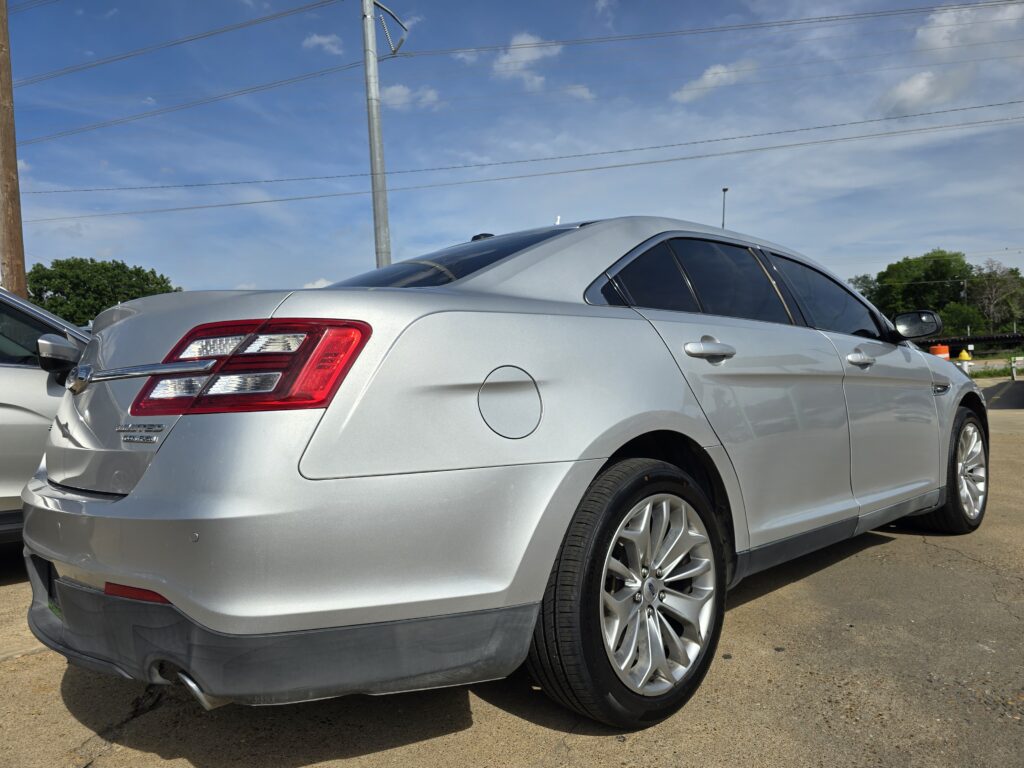 Rear view of a silver sedan parked in a lot, showing the taillight, bumper, and alloy wheel