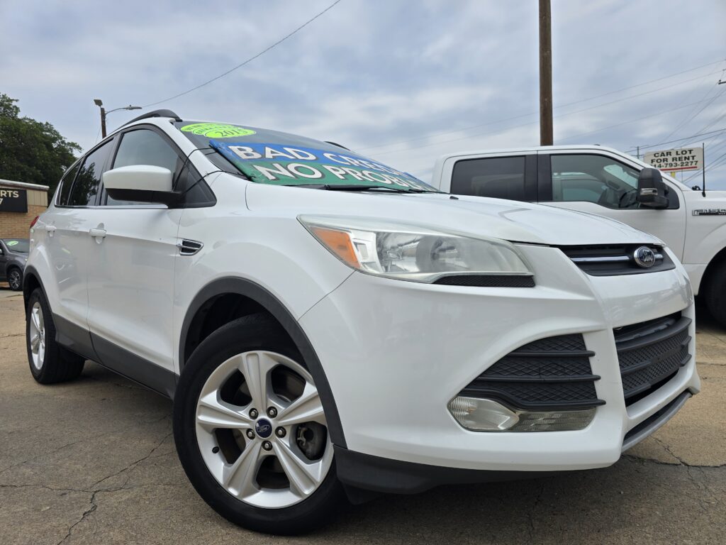 White Ford SUV parked at a dealership with a bright green sale sign on the windshield and large price text visible through the window.