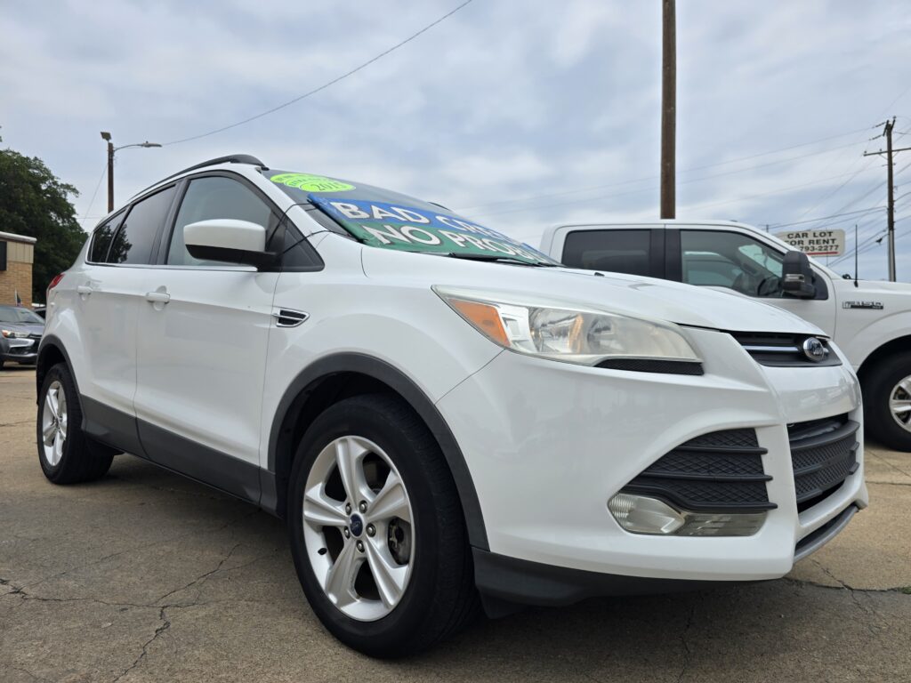 White SUV on a dealership lot with a bright green promotional sign across the windshield.