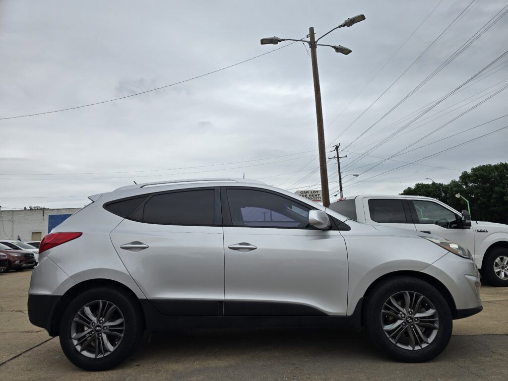 Silver SUV parked in a lot with a wooden utility pole and overhanging streetlights in the cloudy sky backdrop.