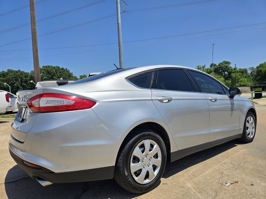 Silver sedan parked in a lot under a clear blue sky, with power poles in the background.