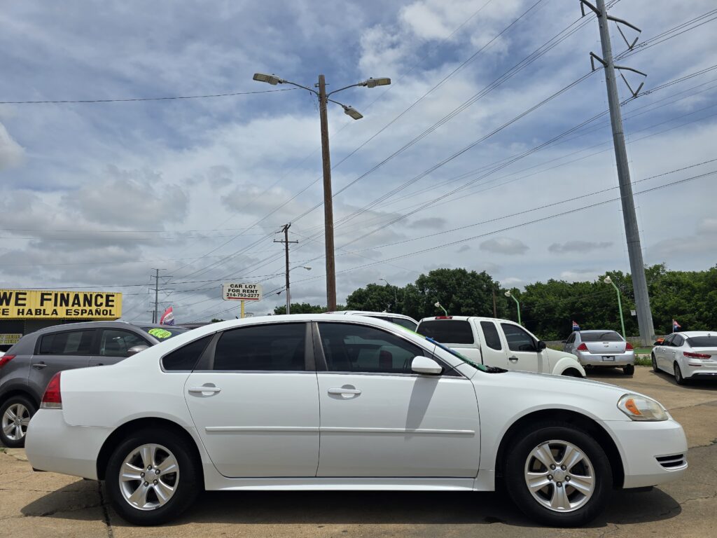 Row of white cars in a dealership lot with overhead power lines and a yellow WE FINANCE sign visible to the left.