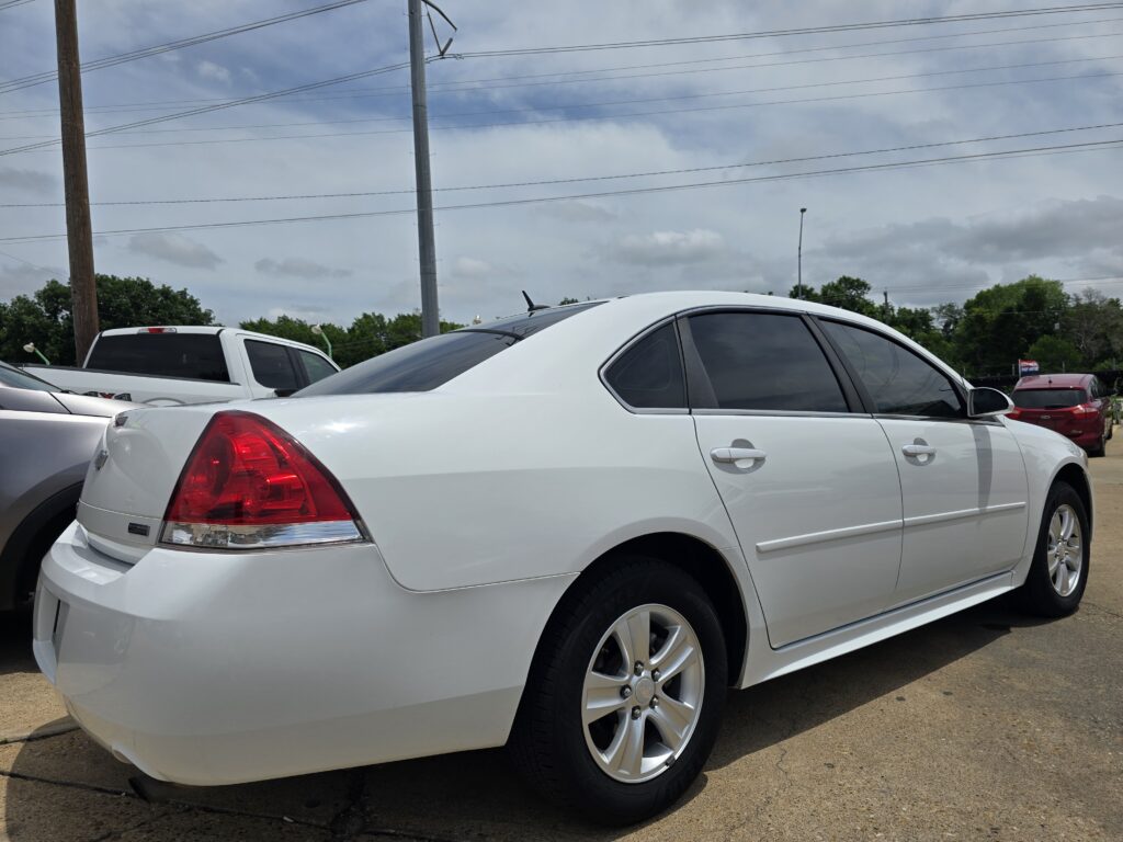 White sedan parked in a lot with power lines and other vehicles in the background