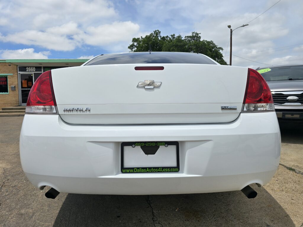Rear view of a white Chevrolet Impala with visible Chevrolet bowtie emblem and taillights, dealership license plate frame reading Dallas Autos 4 Less.