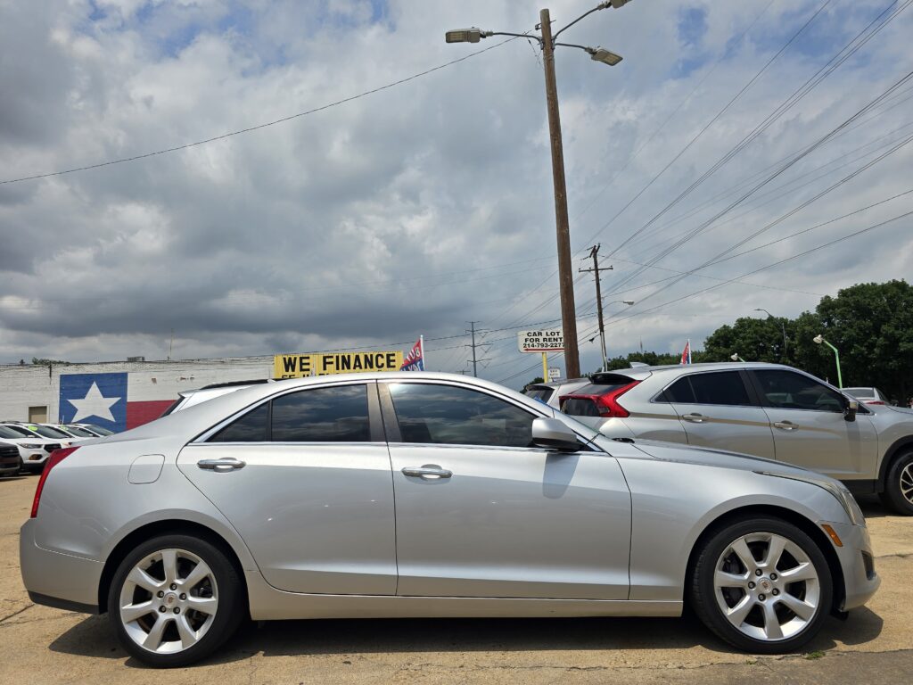 Silver sedan in a car dealership lot, signage reading 'WE FINANCE' against a cloudy sky.