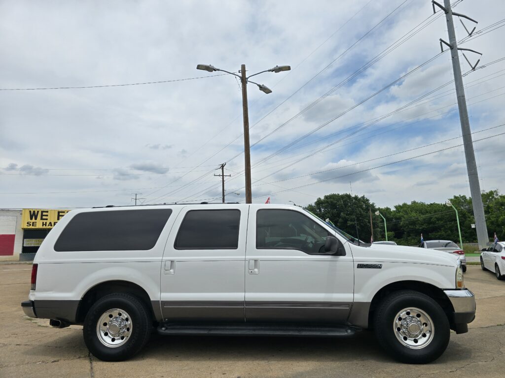 White passenger van parked in a lot with utility poles and overhead power lines in the background.