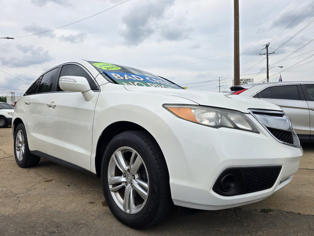 Front-left view of a white sedan in a car dealership lot, with bold green sale sticker on the windshield and cloudy sky above.