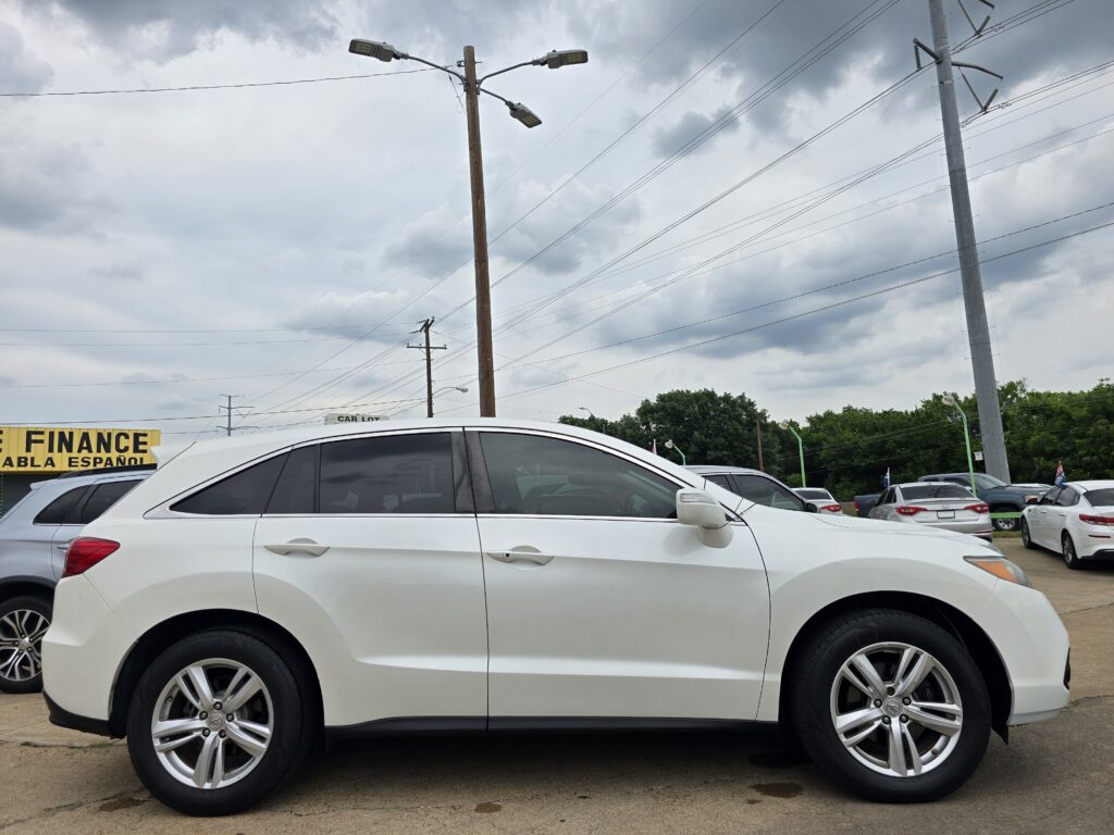White SUV in a car lot with other vehicles, a yellow FINANCE sign, and cloudy sky above.