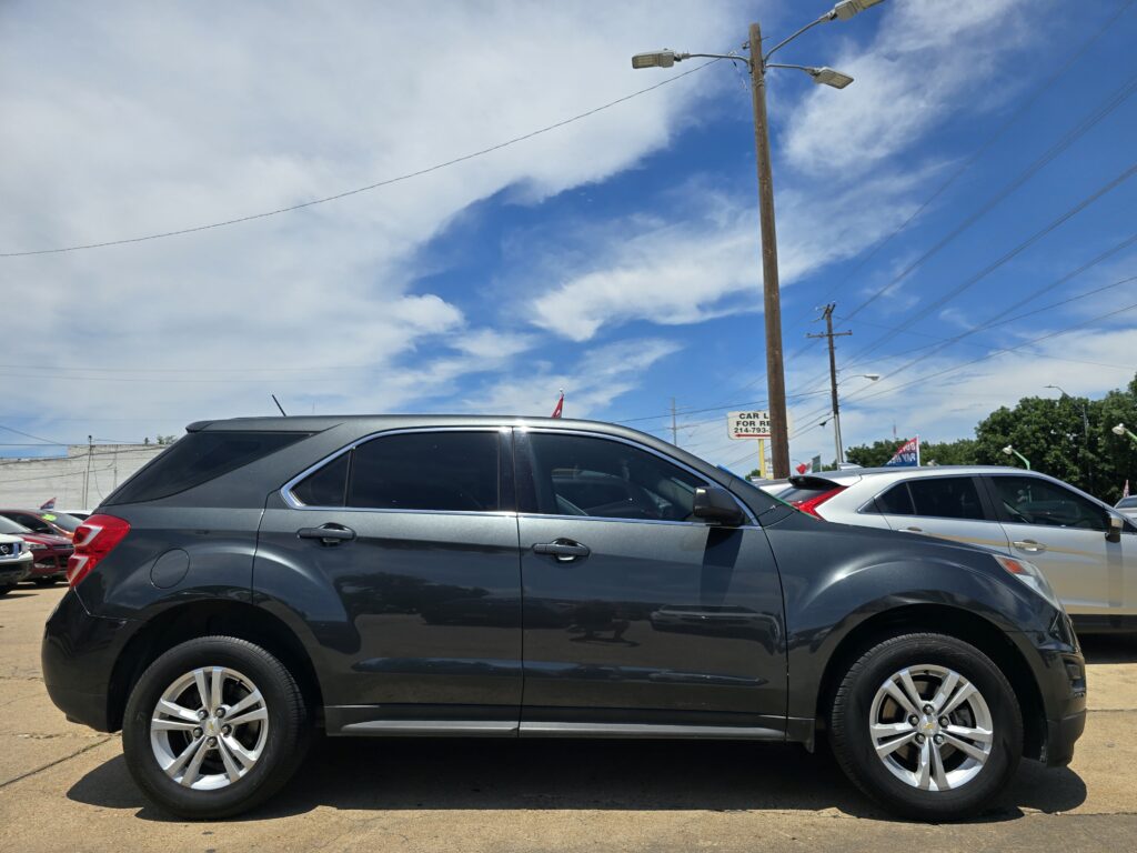 Dark gray SUV parked in a lot with utility poles and power lines against a blue sky.