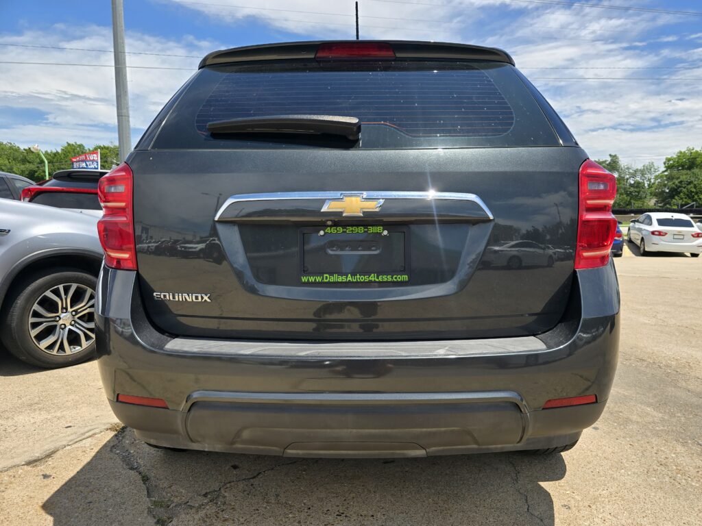 Rear view of a dark gray Chevrolet Equinox with taillights and rear windshield in a parking lot, showing a dealer plate area.