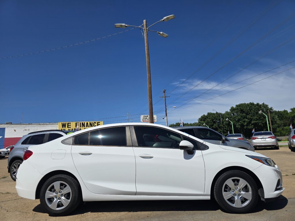 White SUV in a car dealership lot under a clear blue sky with a yellow 'WE FINANCE' sign in the background.