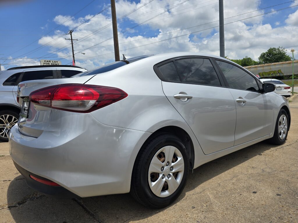 Silver sedan in a car lot, with a 'Car Lot For Rent' sign and a blue sky above.