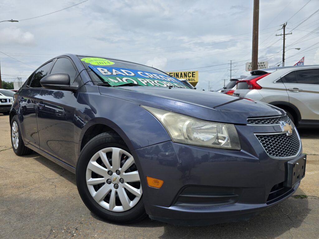 Dark gray Chevrolet sedan on a used-car lot with a large green '2014' sticker and a bold 'BAD CREDIT' banner across the windshield.