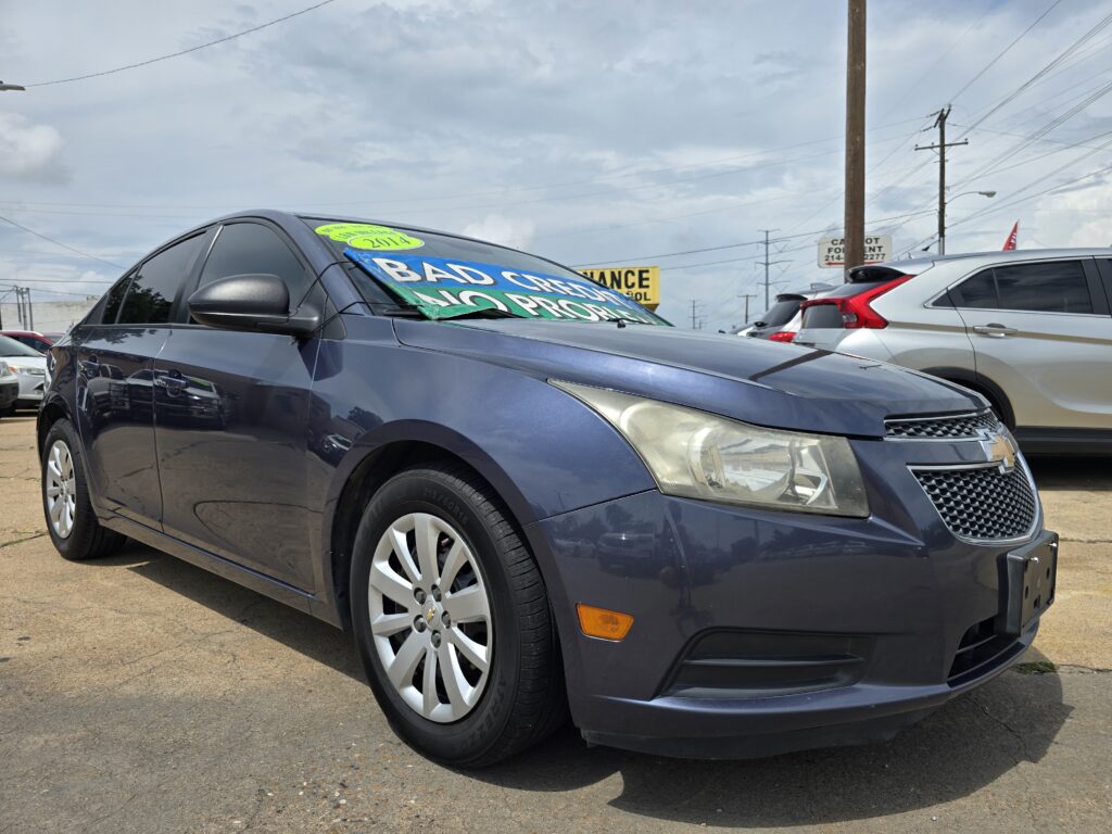 Blue sedan on a dealership lot with a large green sale sign covering the windshield reading ‘BAD CREDIT’ in white letters on the green background