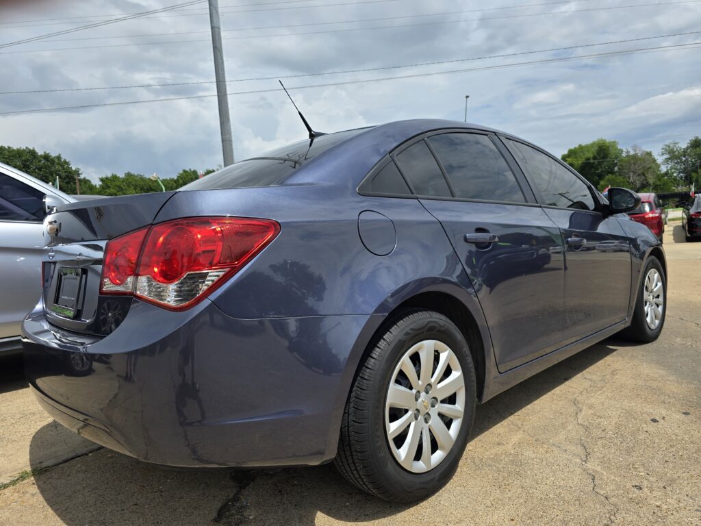 Blue sedan parked outdoors, rear quarter visible with taillight and rear door handle.