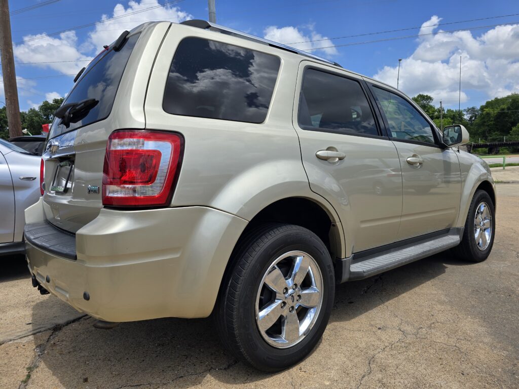 Beige SUV parked on a sunny street, rear and side visible with tinted windows and chrome wheels on a concrete lot54B7