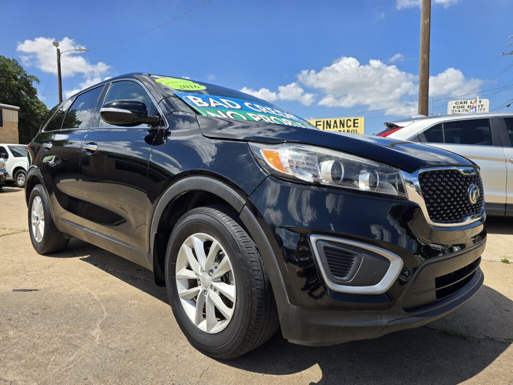 Close-up of a black SUV at a car dealership with bright sale signs on the windshield.