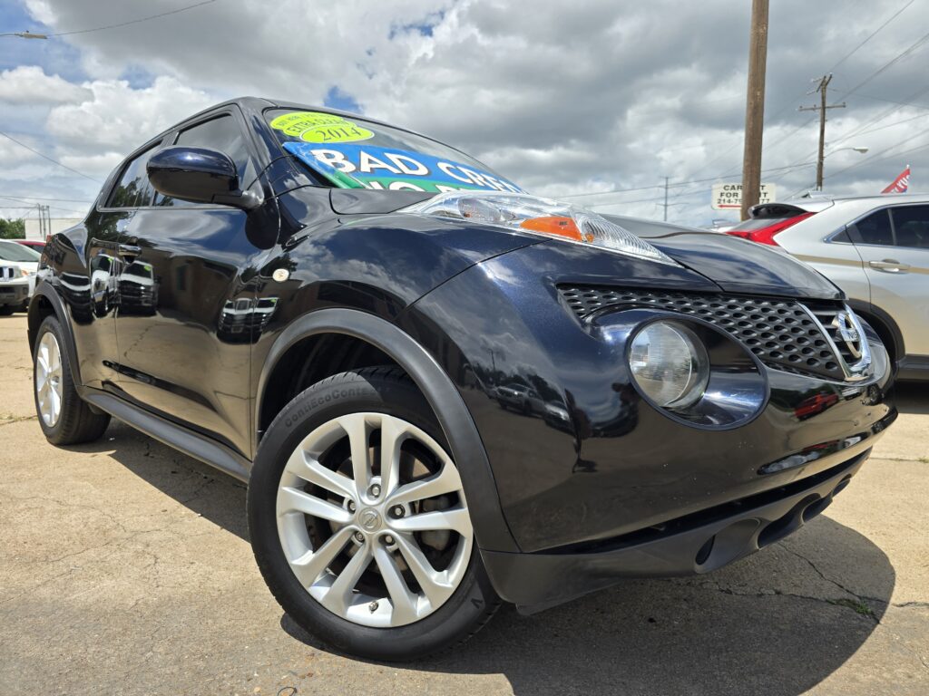 Close-up of a black SUV at a car dealership with a bright blue sale sign across the windshield and a yellow 2014 sticker visible on the glass.