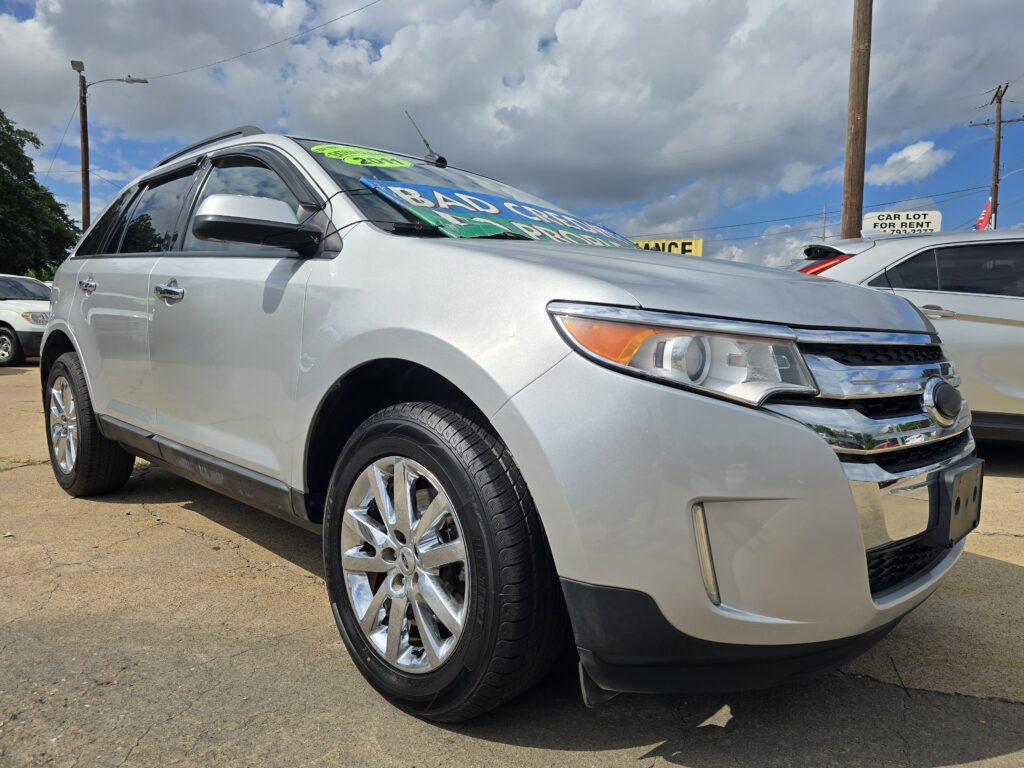 Front-left view of a silver SUV with bright green dealership banners on the windshield in a car lot.
