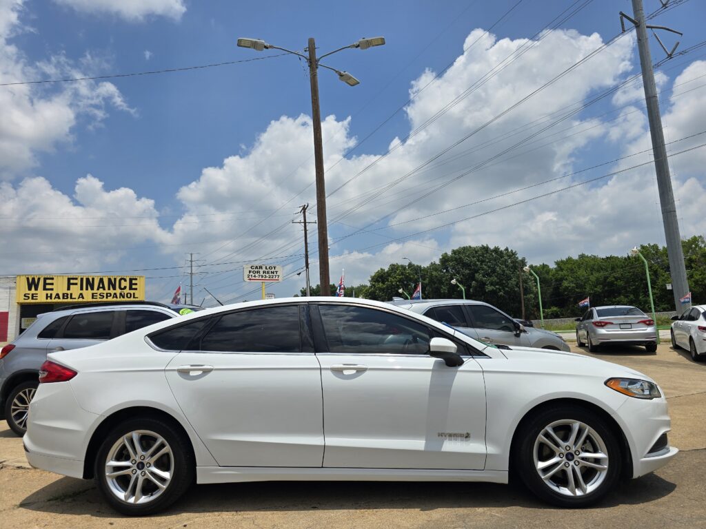 Row of white cars parked in a dealership lot, with a yellow 'WE FINANCE' sign and a blue sky above.