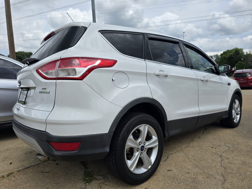 White SUV shown from the rear three-quarter view, parked on a paved lot with tinted windows and red taillights visible.