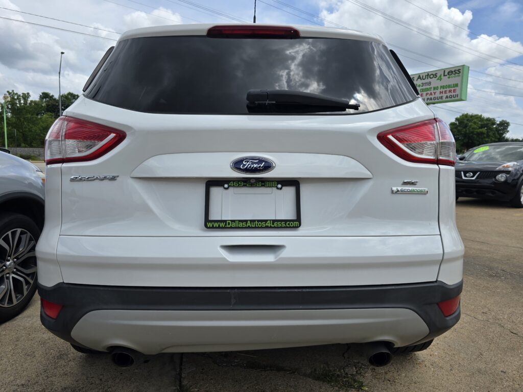 Rear view of a white Ford Escape SUV in a car dealership lot, with a dark rear window and wiper visible.