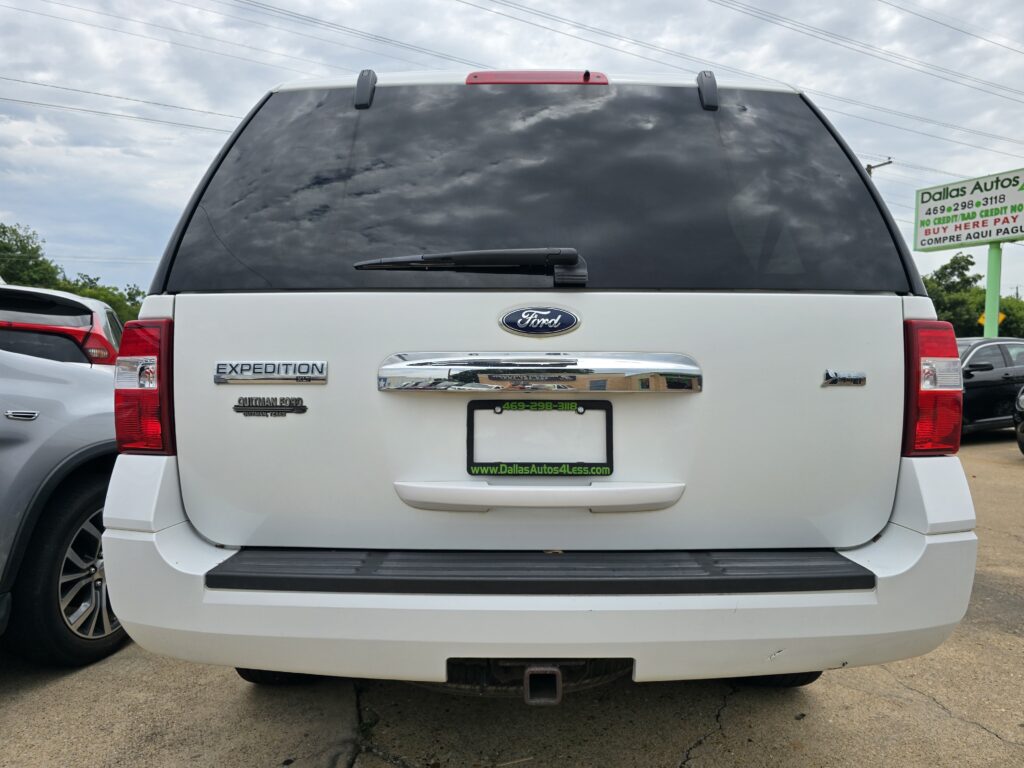 Rear view of a white Ford Expedition SUV with a dealership license plate frame, on a car lot.