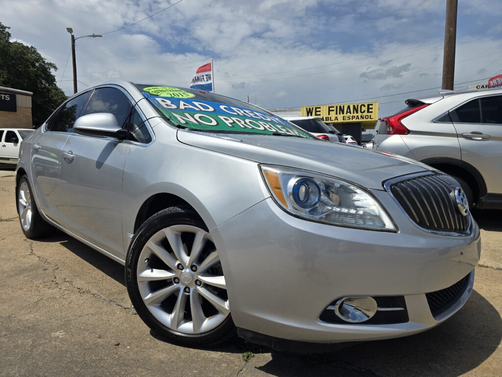 Silver sedan at a car lot with large blue and green promotional banners on the windshield reading 'BAD CARS NO PROBLEMS' and a yellow 'We Finance' sign in the background.