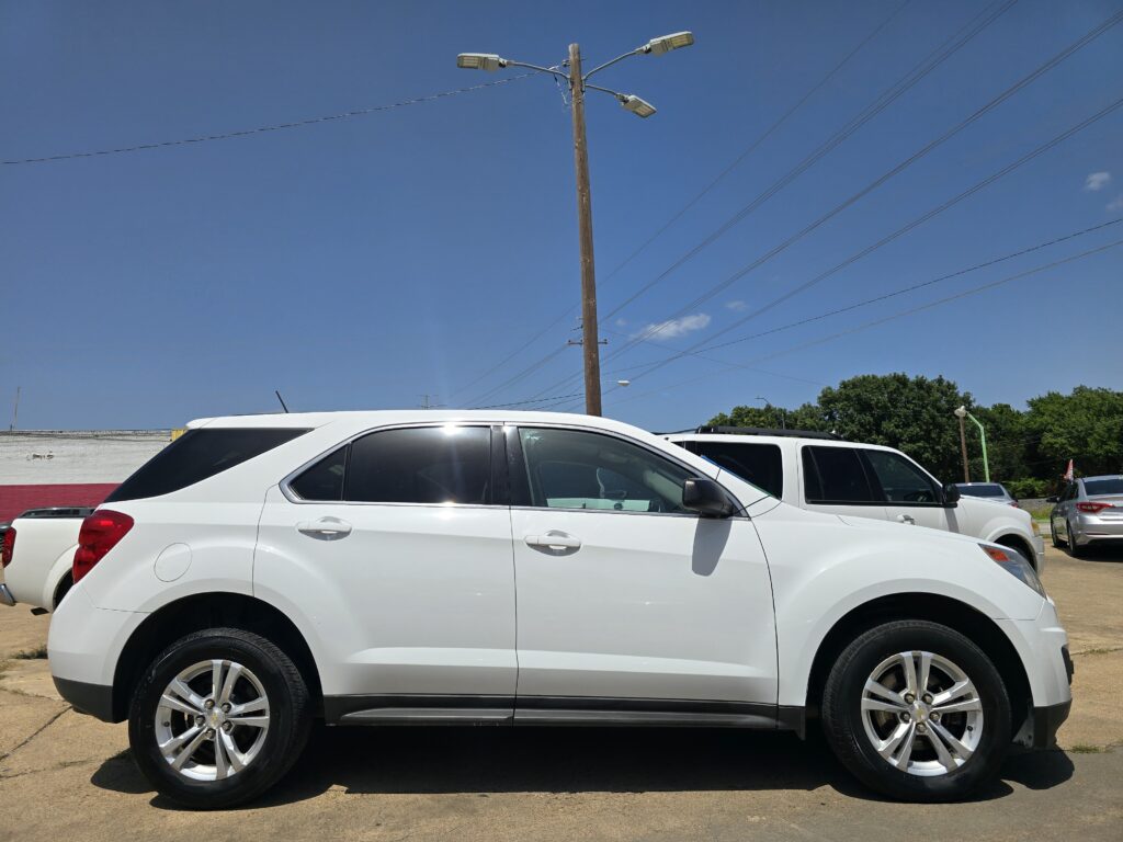 White SUV parked in a lot with a tall wooden utility pole and power lines against a clear blue sky in the background.