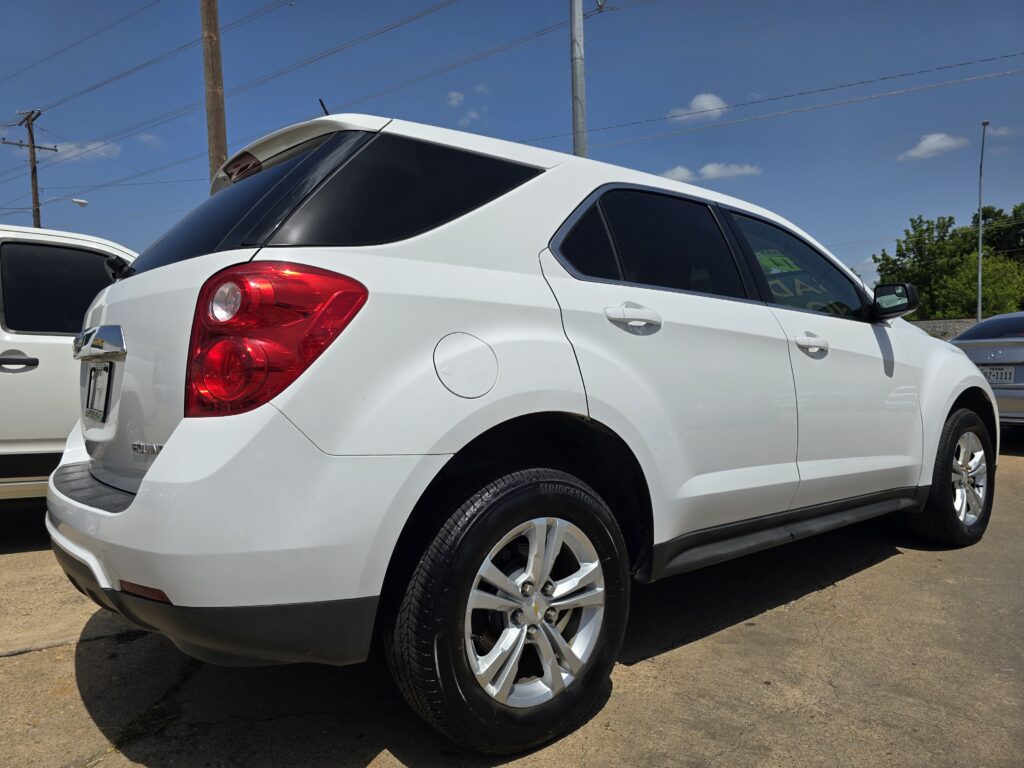 White SUV parked outdoors, viewed from the rear passenger side, with tinted windows and red tail light, on a sunny day.