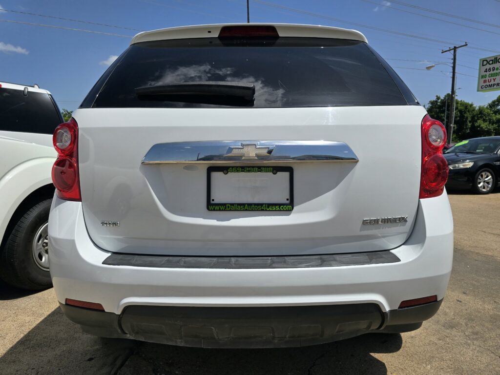 White Chevrolet Equinox seen from the rear at a car lot, with dealer plate frame and green URL text