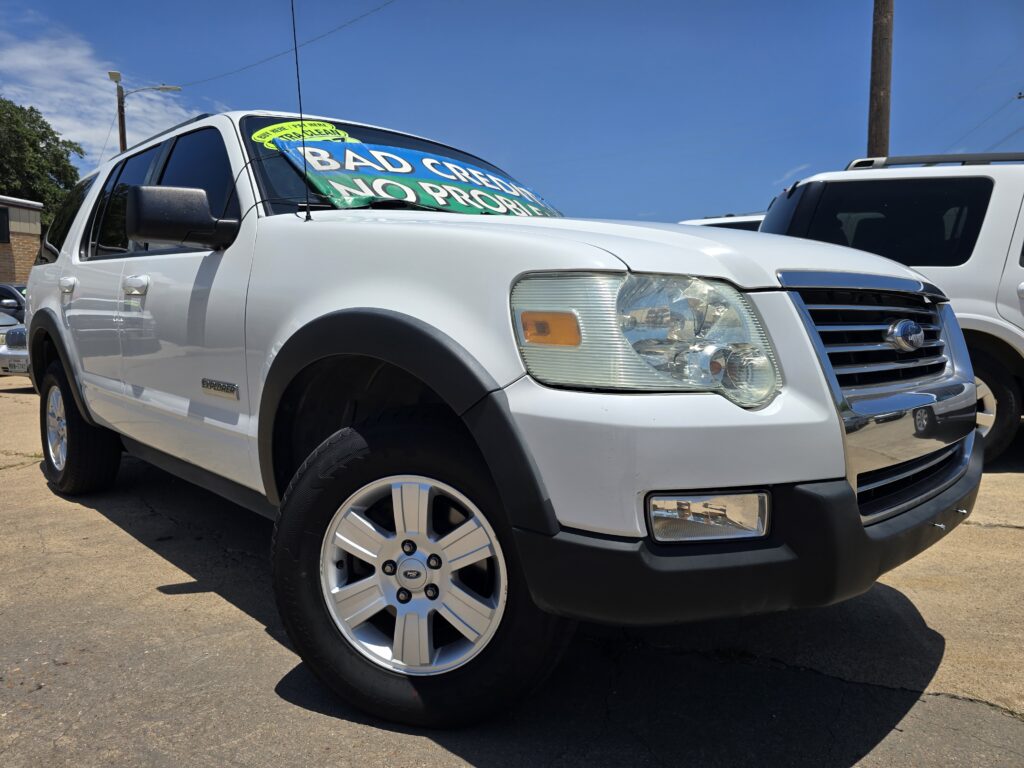 White Ford Explorer in a sunny car lot with a large windshield banner reading BAD CREDIT NO PROBLEM.