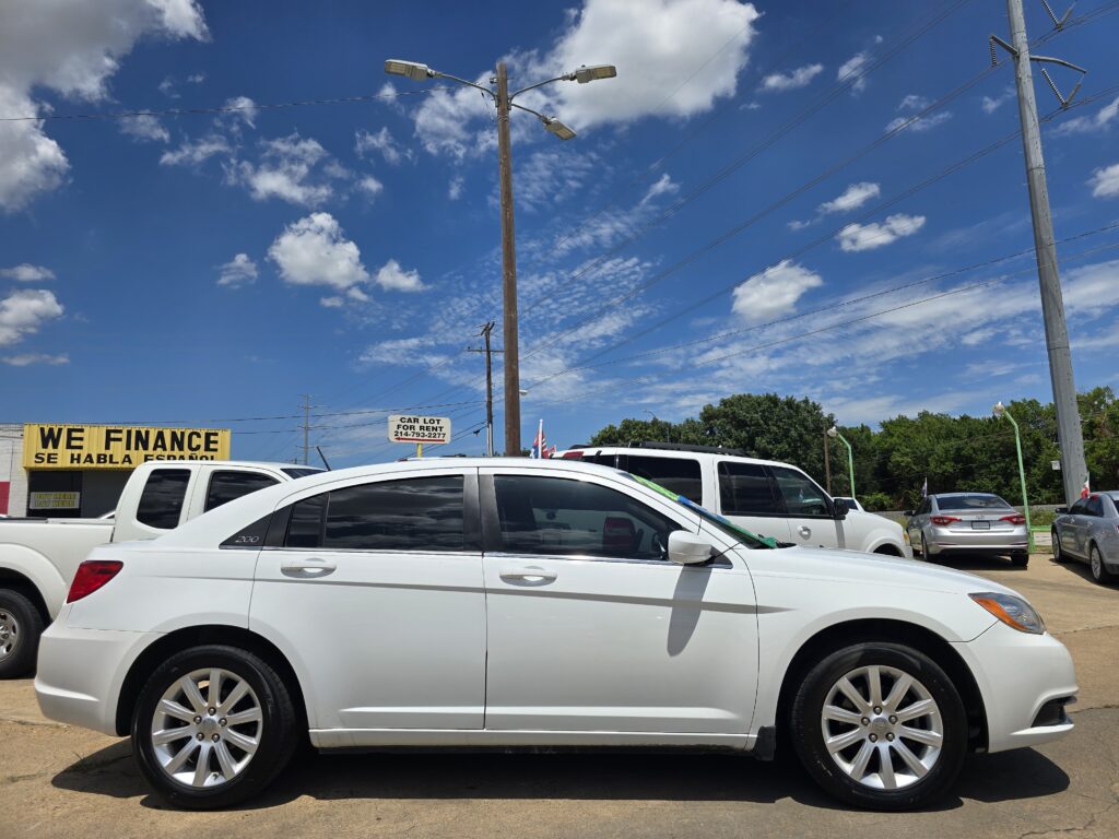 White SUVs parked in a car lot under a bright blue sky with a yellow 'WE FINANCE' sign nearby.