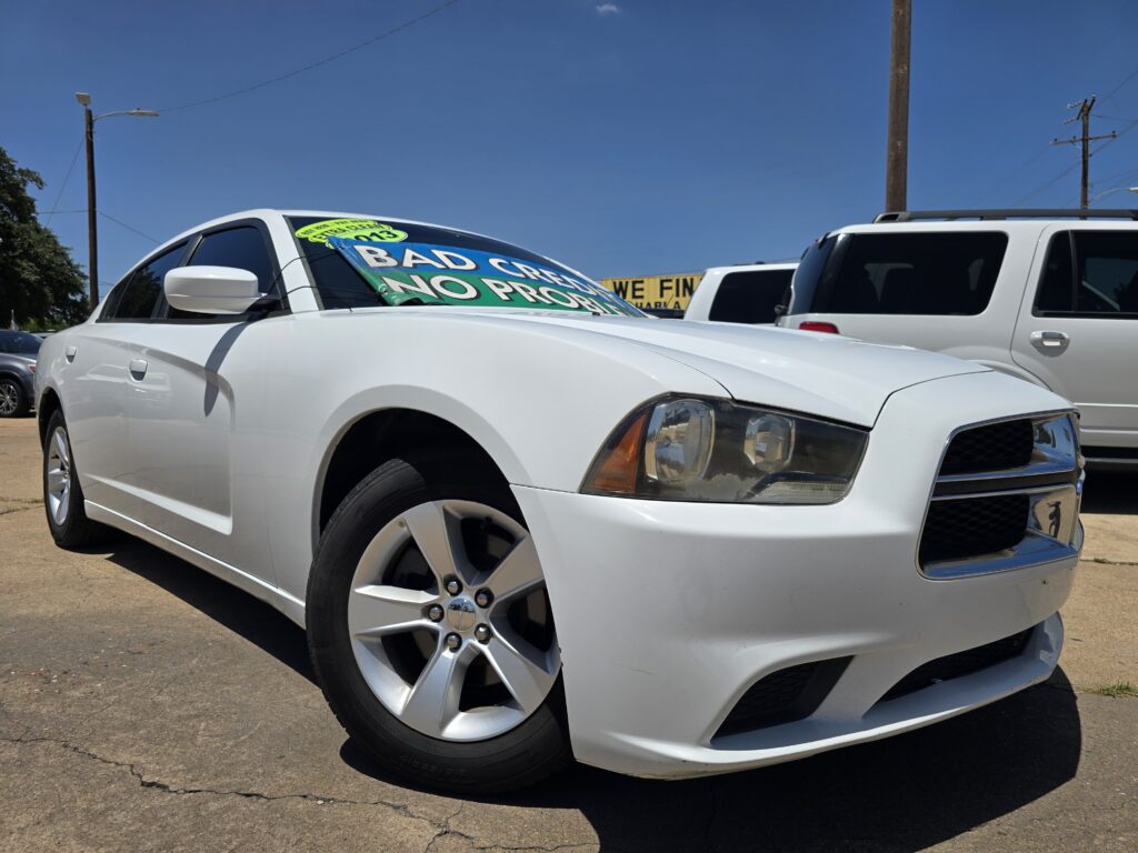 White sedan in a car dealership lot with a large windshield banner that reads 'BAD CREDIT NO PROBLEM'.