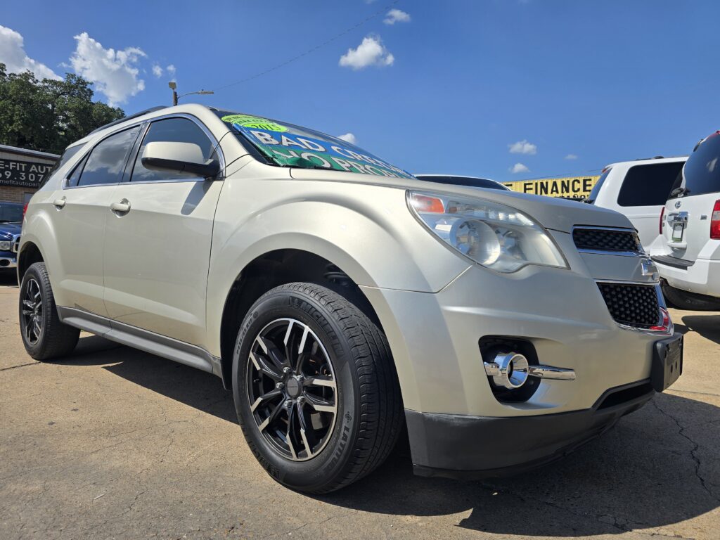 Silver SUV parked at a car dealership lot under a blue sky, with a large sale banner on the windshield.