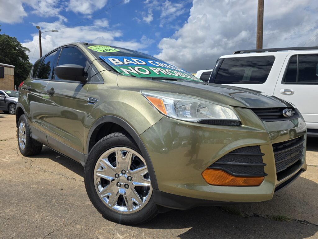 Front-left view of a tan SUV in a dealership lot with a large green sale banner across the windshield (text partially visible).