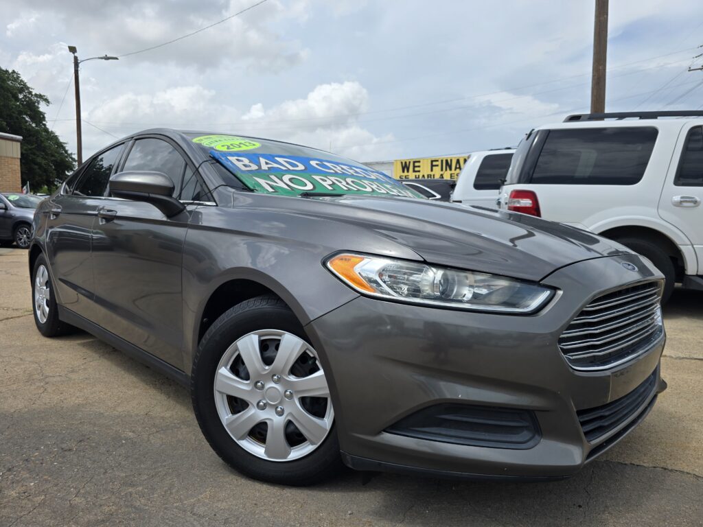 Gray sedan at a car lot with a bold windshield sign reading 'BAD CREDIT NO PROBLEM'