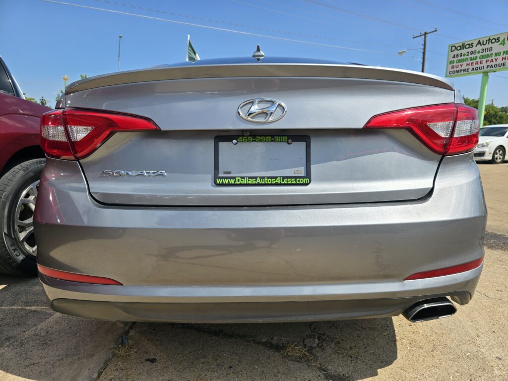 Rear view of a silver Hyundai Sonata at a car dealership, showing the license plate frame reading DallasAutos4Less.com and phone number 469-298-3118.