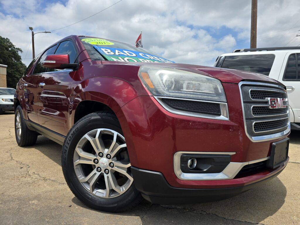 Red GMC SUV on a dealership lot with large green and blue sale banners stretched across the windshield.