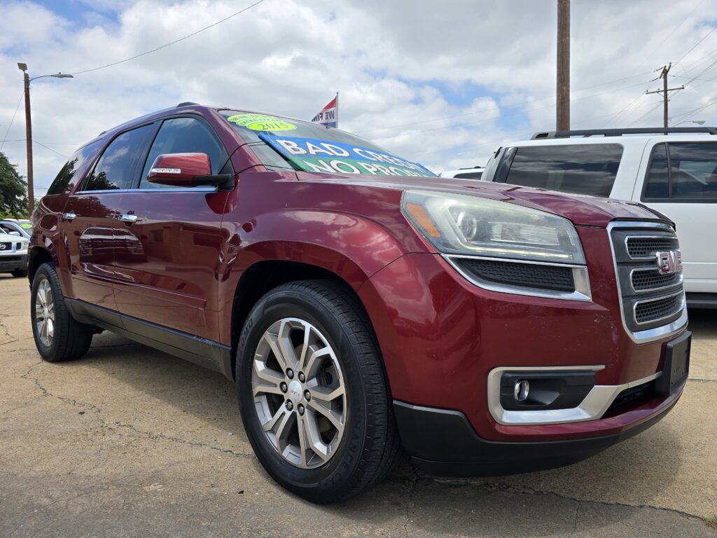 Maroon GMC SUV on a dealership lot with a large windshield sign reading 'BAD CREDIT NO PROBLEM'