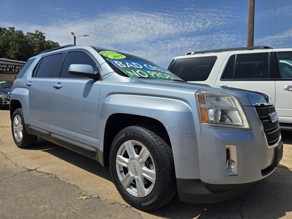 Silver SUV in a car lot with a bold windshield banner: 'BAD CREDIT NO PROBLEM' and a 2015 sticker nearby.