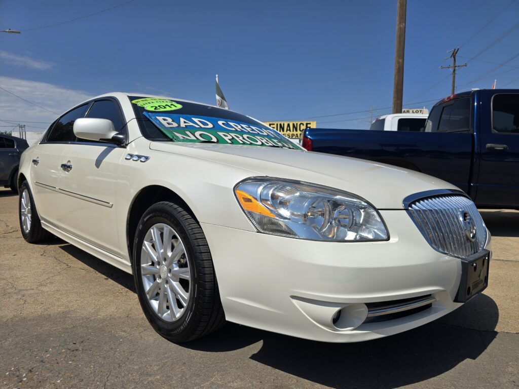 White sedan in a car lot with a large windshield sign that says 'BAD CREDIT NO PROBLEM' in bold letters.